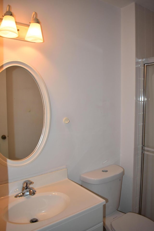 bathroom featuring vanity, walk in shower, and toilet