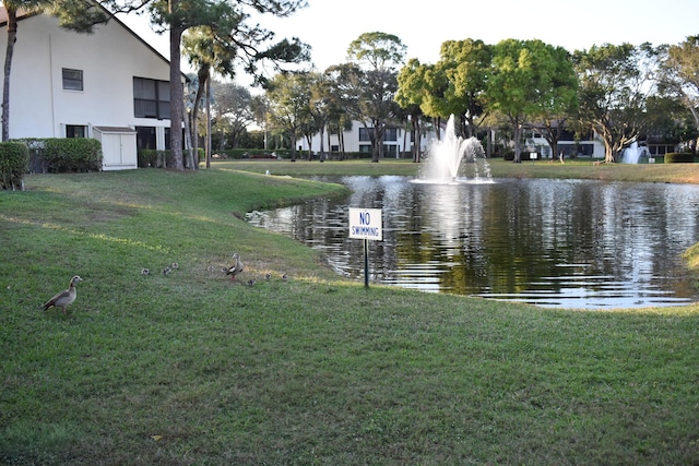 view of property's community with a lawn and a water view