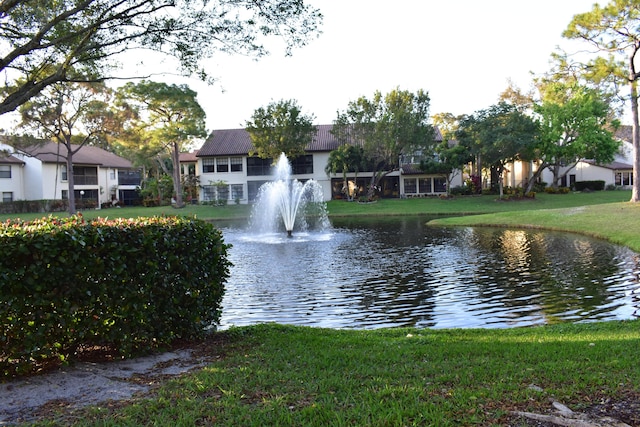 surrounding community with a water view and a lawn