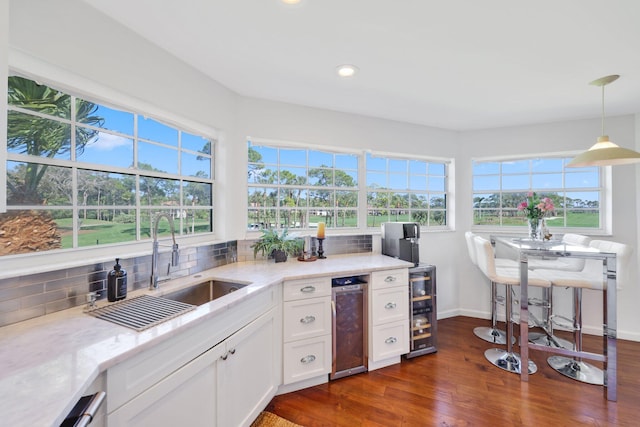 kitchen with pendant lighting, tasteful backsplash, light stone countertops, and white cabinets