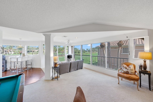 living room with lofted ceiling, ceiling fan, decorative columns, and a textured ceiling