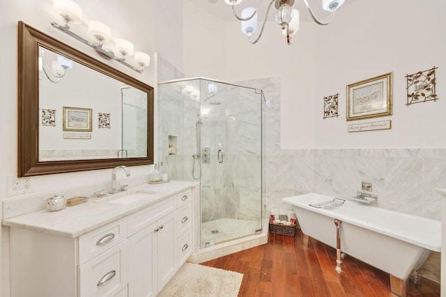 bathroom featuring hardwood / wood-style flooring, an inviting chandelier, tile walls, vanity, and separate shower and tub