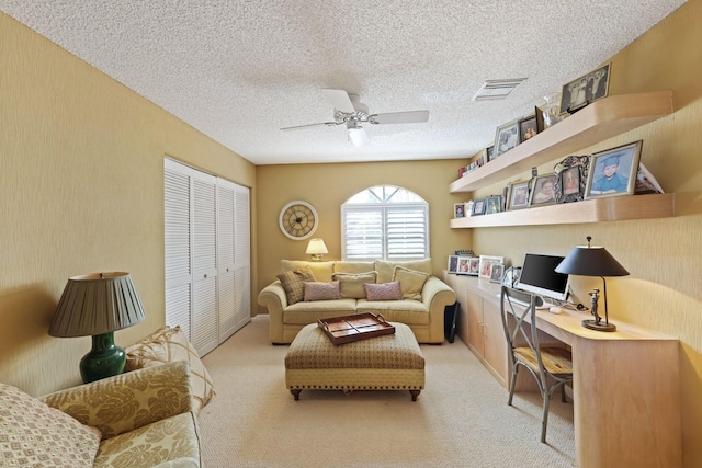 carpeted living room with a textured ceiling, built in desk, and ceiling fan