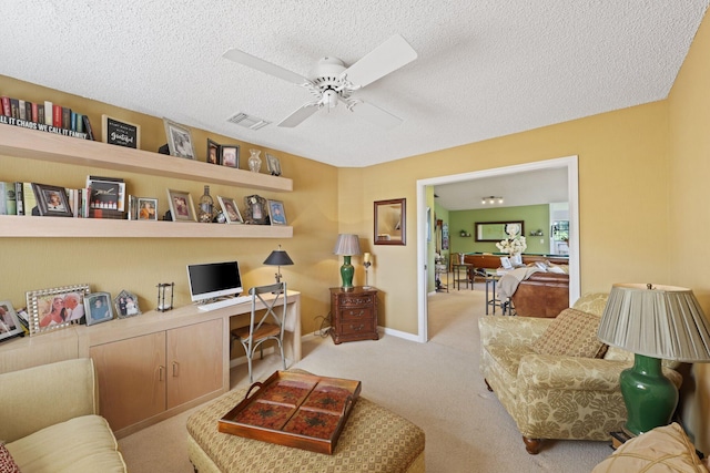 office area featuring ceiling fan, built in desk, light carpet, and a textured ceiling