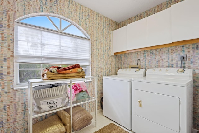 clothes washing area with cabinets, plenty of natural light, washer and dryer, and light tile patterned floors