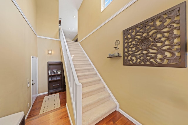 stairway with a high ceiling and wood-type flooring