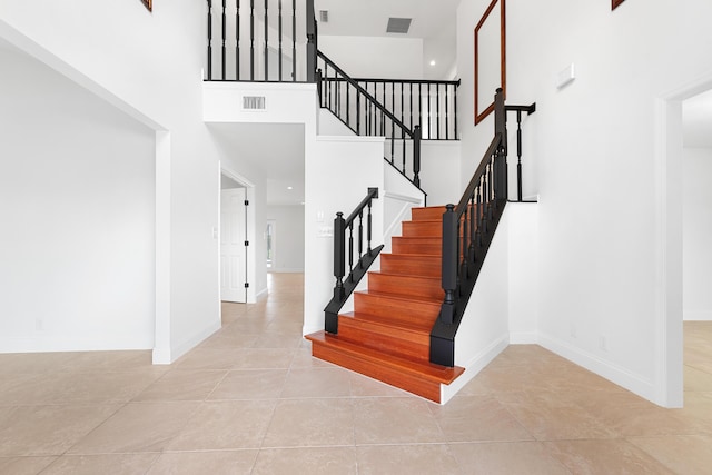 stairs with a towering ceiling and tile patterned floors