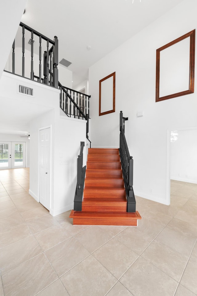 staircase with tile patterned flooring, a towering ceiling, and french doors