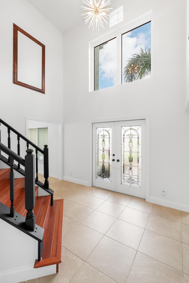 entrance foyer with an inviting chandelier, french doors, a high ceiling, and light tile patterned flooring