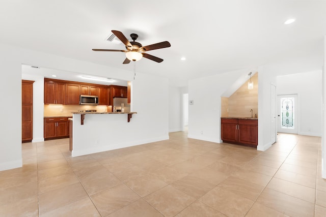 unfurnished living room featuring ceiling fan, sink, and light tile patterned floors