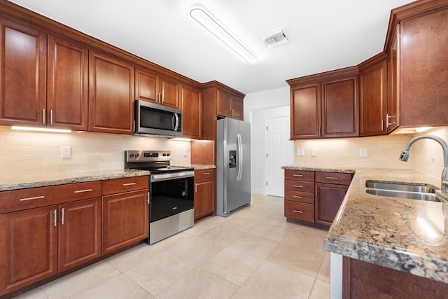 kitchen with light tile patterned flooring, appliances with stainless steel finishes, sink, and light stone counters