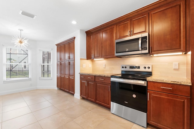 kitchen featuring appliances with stainless steel finishes, backsplash, a chandelier, light tile patterned floors, and light stone countertops