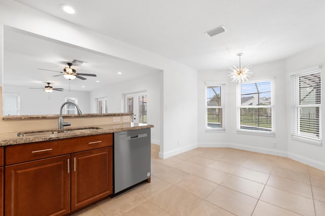 kitchen featuring sink, light stone counters, hanging light fixtures, light tile patterned floors, and stainless steel dishwasher