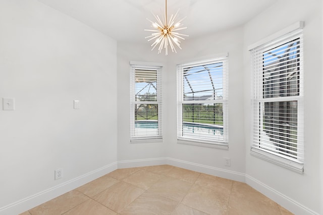 tiled spare room with a chandelier