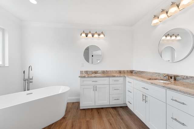 bathroom with crown molding, vanity, hardwood / wood-style floors, and a tub