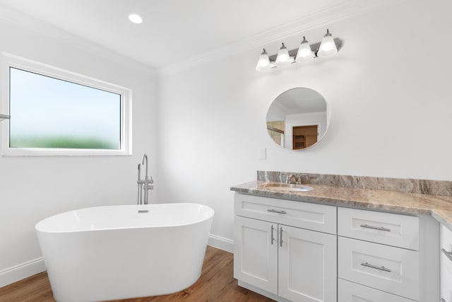 bathroom with hardwood / wood-style floors, crown molding, a washtub, and vanity