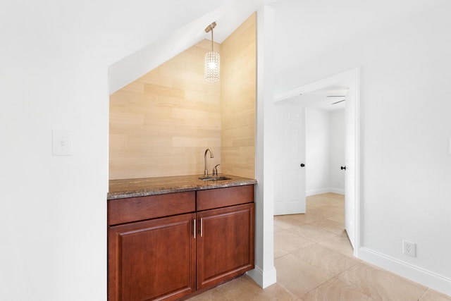 bar with sink, dark stone counters, and decorative light fixtures