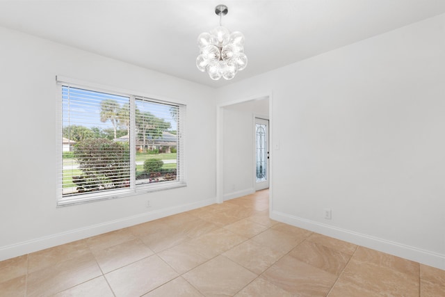 tiled spare room featuring a notable chandelier