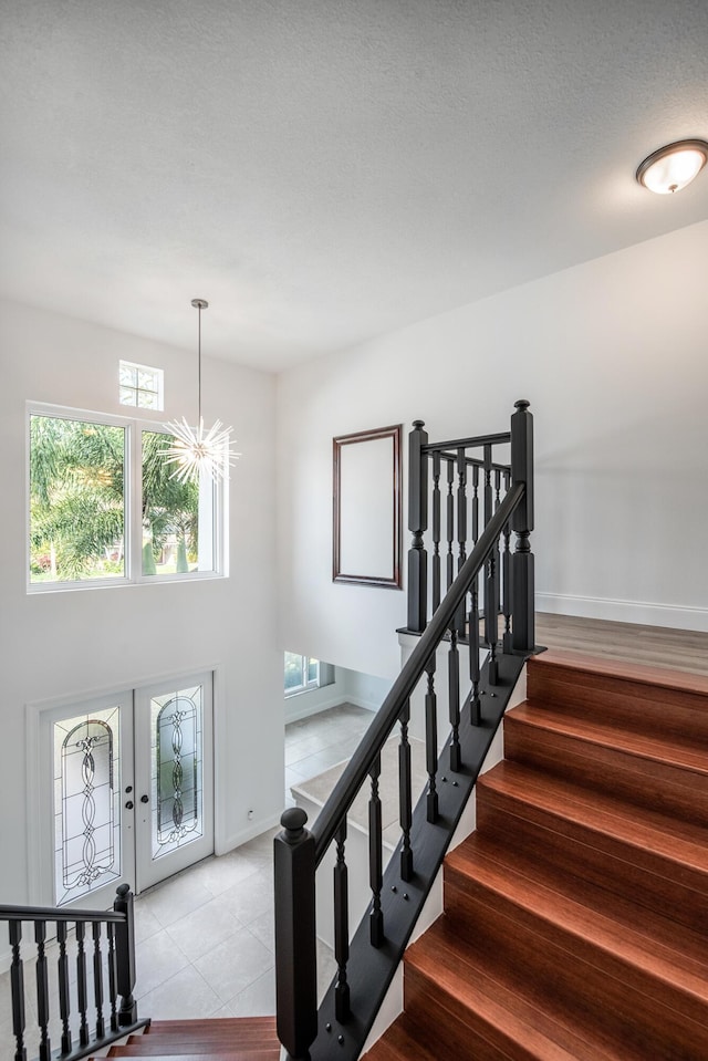 staircase with an inviting chandelier and french doors