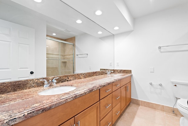 bathroom with a shower with door, vanity, tile patterned floors, and toilet