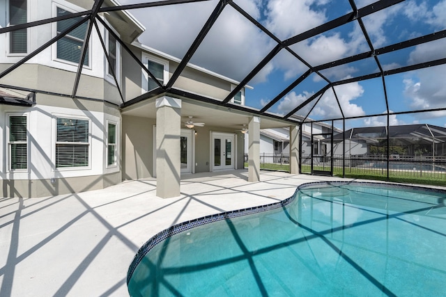 view of swimming pool featuring french doors, ceiling fan, a patio, and glass enclosure