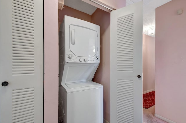 washroom featuring stacked washer / dryer and light carpet