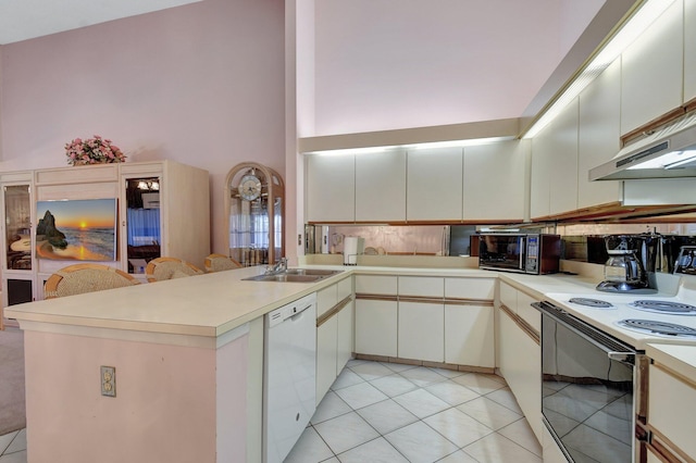 kitchen featuring sink, light tile patterned floors, white appliances, a high ceiling, and kitchen peninsula