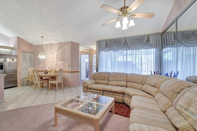 tiled living room with ceiling fan with notable chandelier and vaulted ceiling