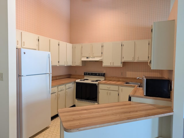 kitchen with cream cabinetry, sink, white appliances, and kitchen peninsula