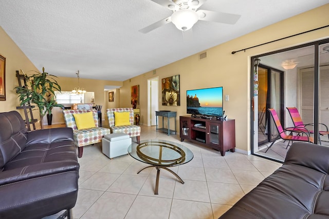 living room featuring ceiling fan with notable chandelier, visible vents, a textured ceiling, and light tile patterned floors