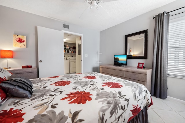 bedroom featuring washing machine and clothes dryer, visible vents, a ceiling fan, light tile patterned flooring, and a textured ceiling