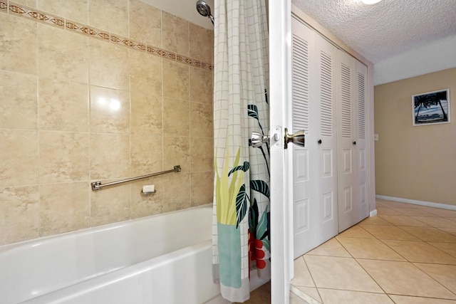 bathroom with baseboards, tile patterned floors, shower / bath combination with curtain, a textured ceiling, and a closet