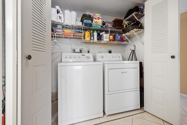 washroom featuring laundry area, independent washer and dryer, a textured ceiling, and light tile patterned floors