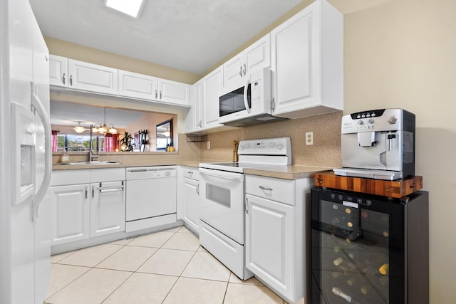 kitchen with white appliances, tasteful backsplash, light tile patterned floors, wine cooler, and a sink