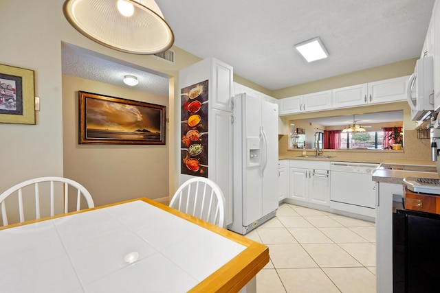 kitchen with light tile patterned flooring, white appliances, a sink, visible vents, and white cabinets