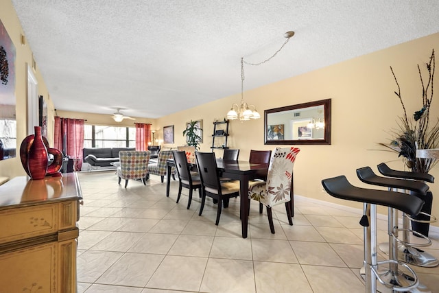 dining area with light tile patterned floors, a textured ceiling, and ceiling fan with notable chandelier