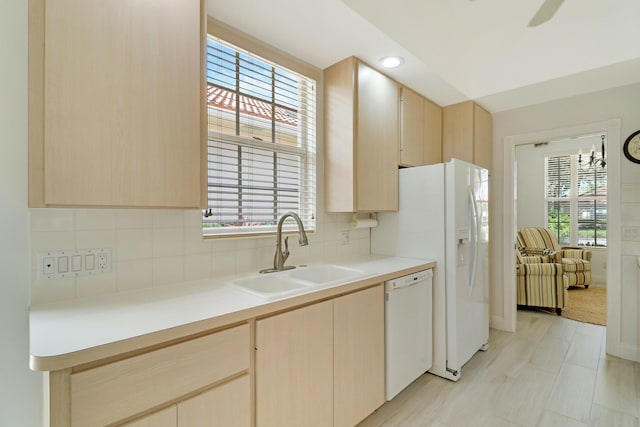 kitchen featuring sink, light brown cabinetry, white dishwasher, and decorative backsplash