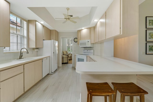 kitchen featuring white appliances, a kitchen breakfast bar, and kitchen peninsula