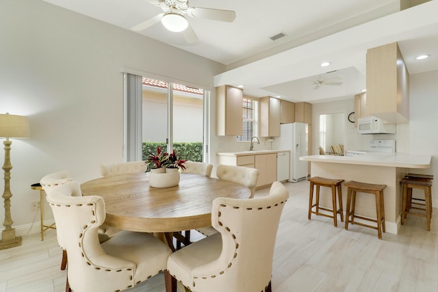 dining space with sink, light hardwood / wood-style floors, and ceiling fan