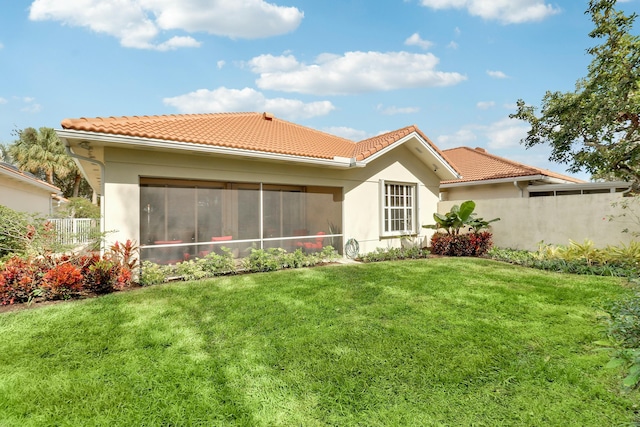 back of house featuring a yard and a sunroom