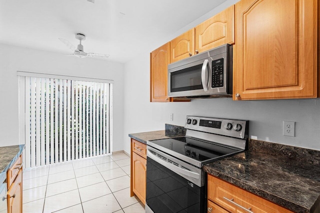 kitchen with ceiling fan, appliances with stainless steel finishes, dark stone counters, and light tile patterned floors