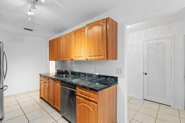 kitchen with dark stone counters, black dishwasher, sink, and light tile patterned floors