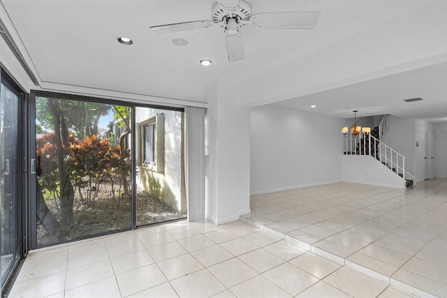 tiled spare room with ceiling fan with notable chandelier