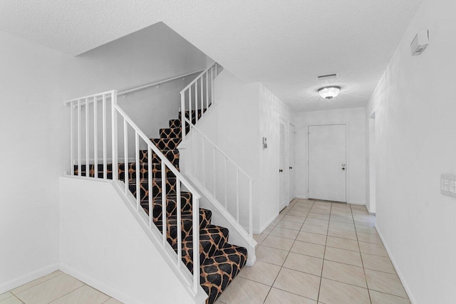 stairs with tile patterned floors and a textured ceiling