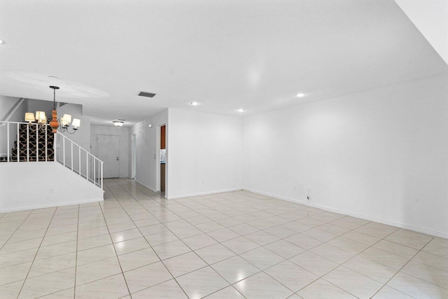 tiled spare room featuring a notable chandelier