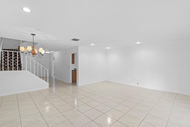 tiled spare room with an inviting chandelier