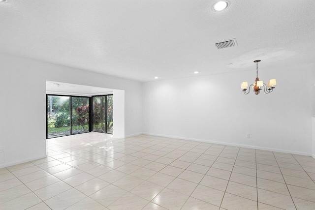 unfurnished room with a textured ceiling and a notable chandelier