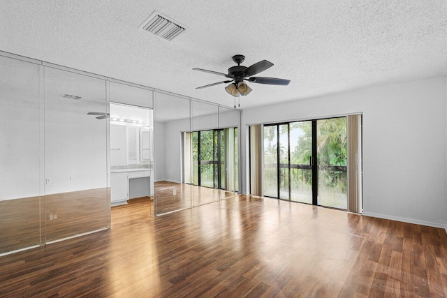 empty room featuring ceiling fan, hardwood / wood-style floors, and a textured ceiling