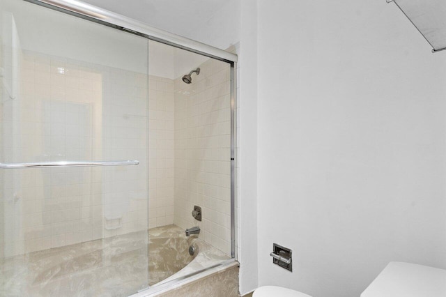 bathroom featuring enclosed tub / shower combo and toilet