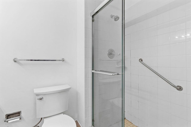 bathroom with a shower with shower door and toilet